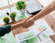 Handshake above eco-themed financial documents