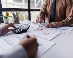 People reviewing financial charts with calculator