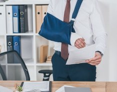 Man with arm in sling holding paperwork to show concept of workers' compensation claims