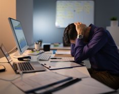 Man stressed at work with head in hands 