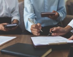 People signing documents at meeting table