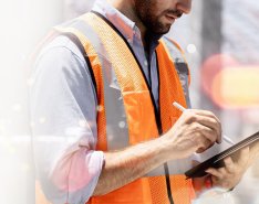 Man in construction vest using tablet, with tech concept background