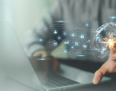 tech symbols surround computer with hand touching the AI symbol