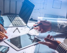 two workers pointing to tablet and laptop