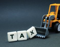 wheel loader scooping up blocks spelling "tax" 