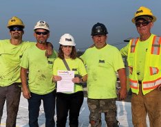 Kara McCaffrey holding a toolbox talk with a roofing crew at Houck