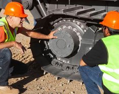 Two men in hard hats and vests inspecting dozer 