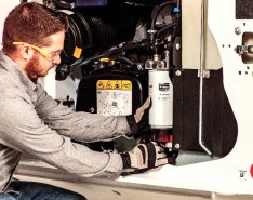 A man in safety glasses and gloves fixes a machine