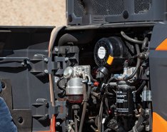 A construction worker looks at the inner working of a piece of machinery