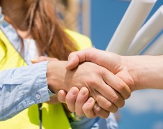Two individuals in bright safety vest shake hands