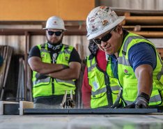 5 workers in green vests and white hard hats 