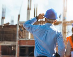 Two people in vests and hard hats looking at jobsite