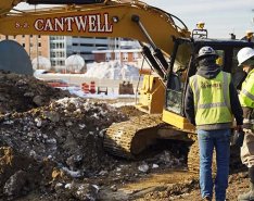 Two construction workers on jobsite in front of S.J. Cantwell machine