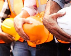 5 workers in a line holding hardhats