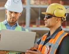 Four construction workers looking at laptop