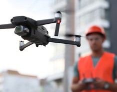 A construction worker in bright safety gear flies a drone