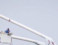 Utility workers in buckets, working on lines