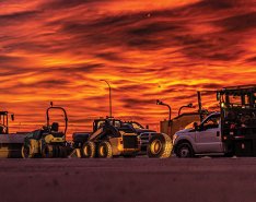 Construction fleet in front of vibrant background/Adobe Stock