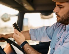 A man looks at his phone while driving