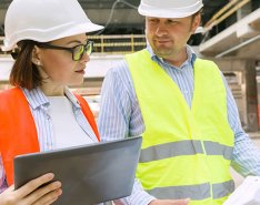 Two workers looking at paper and tablet