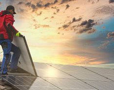 Two workers on roof laying solar panels