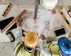 Three people in hard hats looking at plans