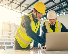 Two construction workers using laptop
