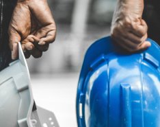 Two hands holding hardhats