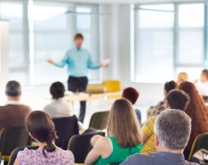 A classroom full of adult students watches a presentation