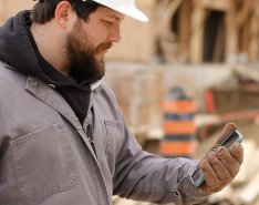 A man in a hard hat looks at his phone