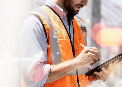 Man in construction vest using tablet, with tech concept background