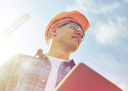 Construction worker in hard hat and goggles smiling on the jobsite