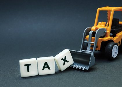 wheel loader scooping up blocks spelling "tax" 