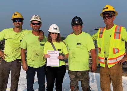 Kara McCaffrey holding a toolbox talk with a roofing crew at Houck
