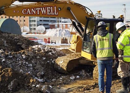 Two construction workers on jobsite in front of S.J. Cantwell machine
