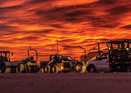 Construction fleet in front of vibrant background/Adobe Stock