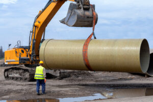 excavator hoisting a concrete pipe