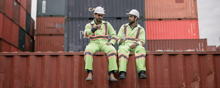 Two construction workers sitting on a ledge and talking