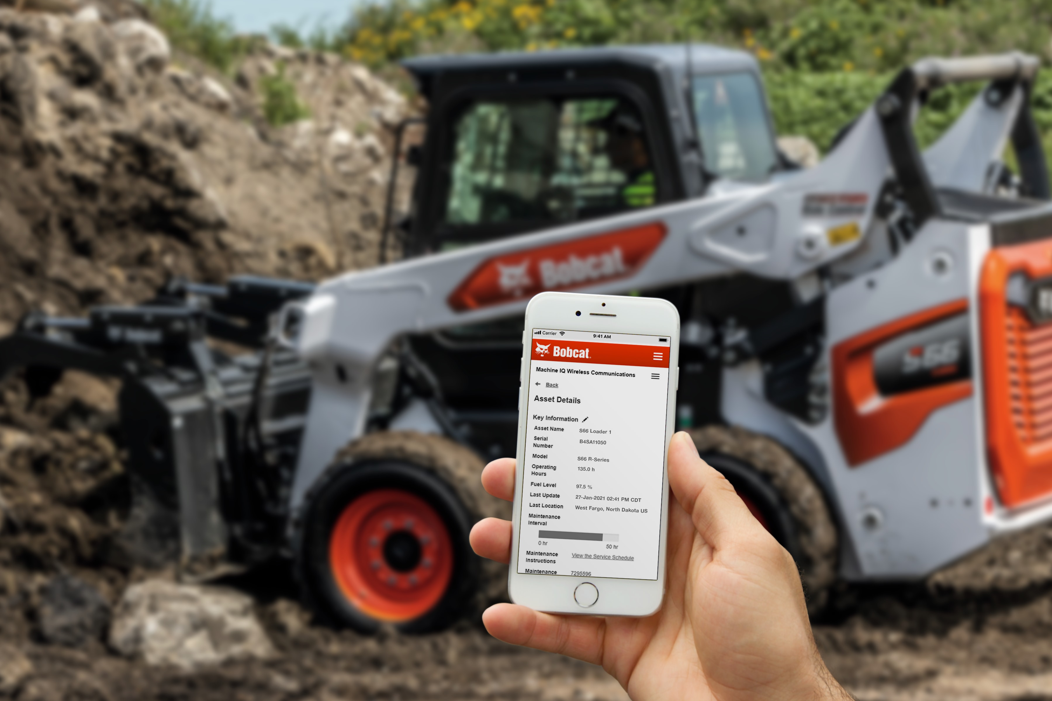 Bobcat telematics app on mobile phone in front of Bobcat equipment
