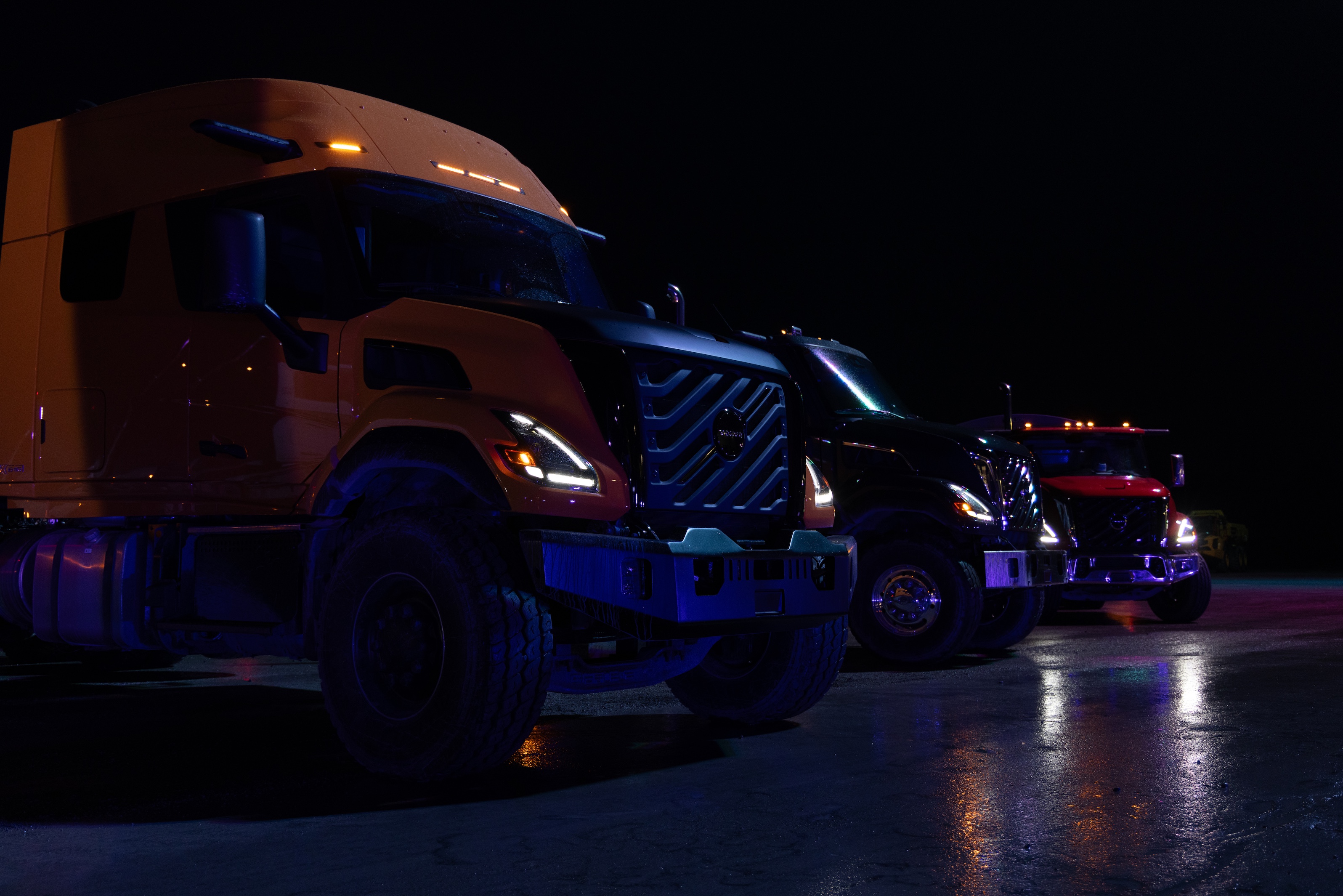 Volvo VNX vocational trucks lined up in the dark 