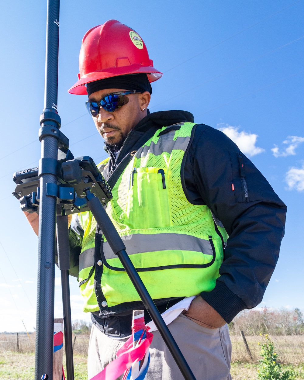 Construction worker in vest and hard hat using Leica tools