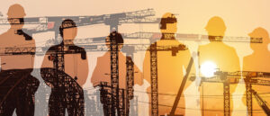 silhouette of construction workers in front of construction equipment