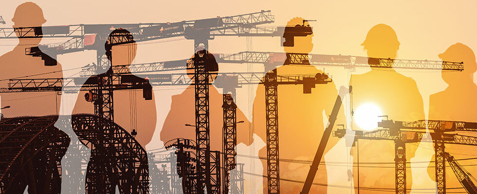 silhouette of construction workers in front of construction equipment