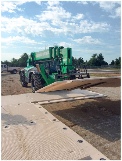 Telehandler placing mats on construction roadway