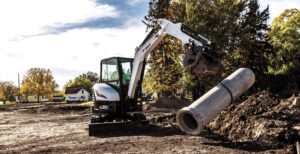 Excavator lifting concrete pipe at construction site
