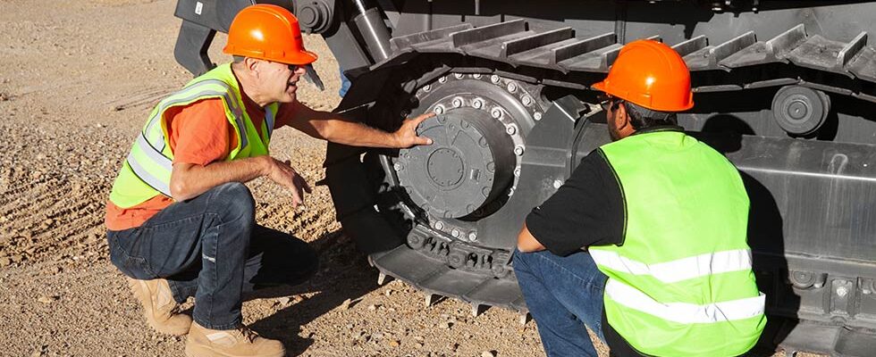 construction workers inspecting a dozer tire