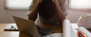 person at computer, with head in hands