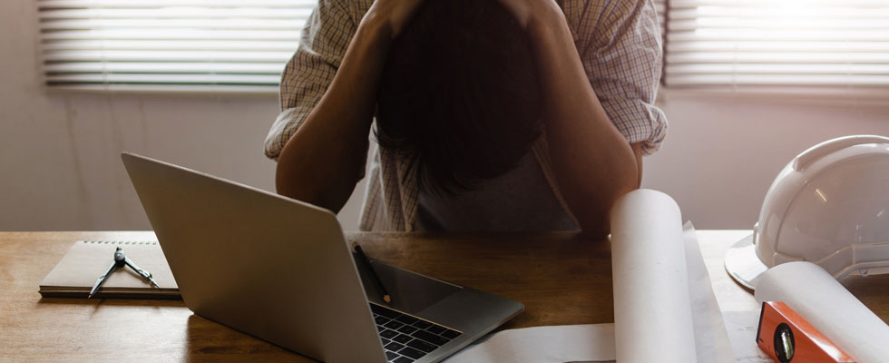 person at computer, with head in hands